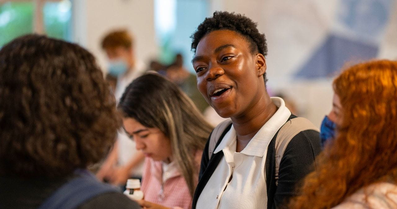 A group of students chatting together in a lively classroom environment.