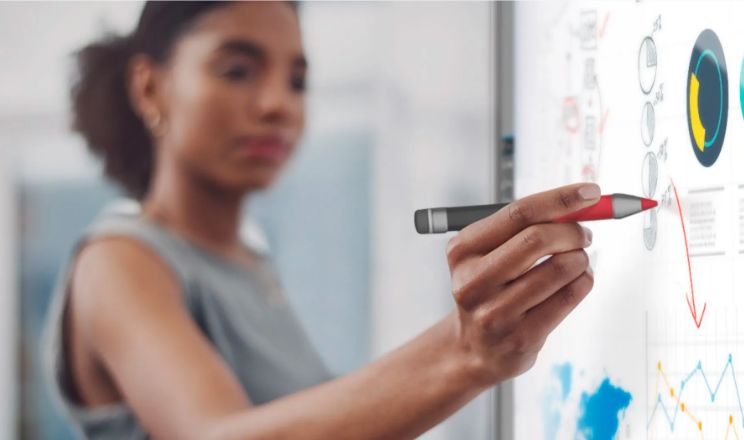 Woman using a digital ink pen to interact with a graph on a SMART interactive display, illustrating data analysis in progress.