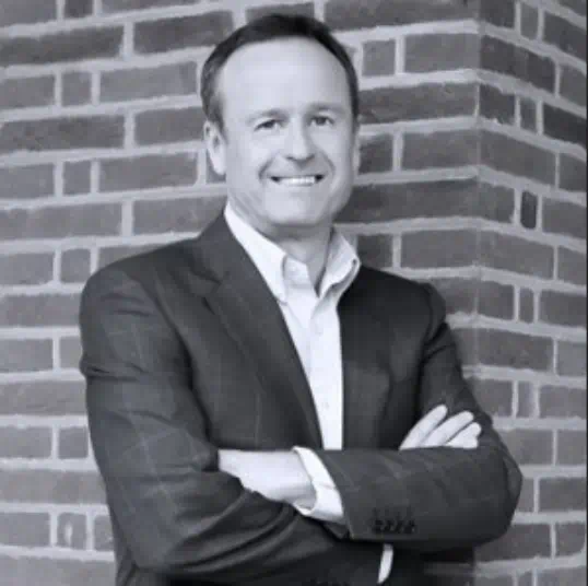 Peter Birkholm, Founder and Managing Director of ITZ, smiling while standing against a brick wall with arms crossed.