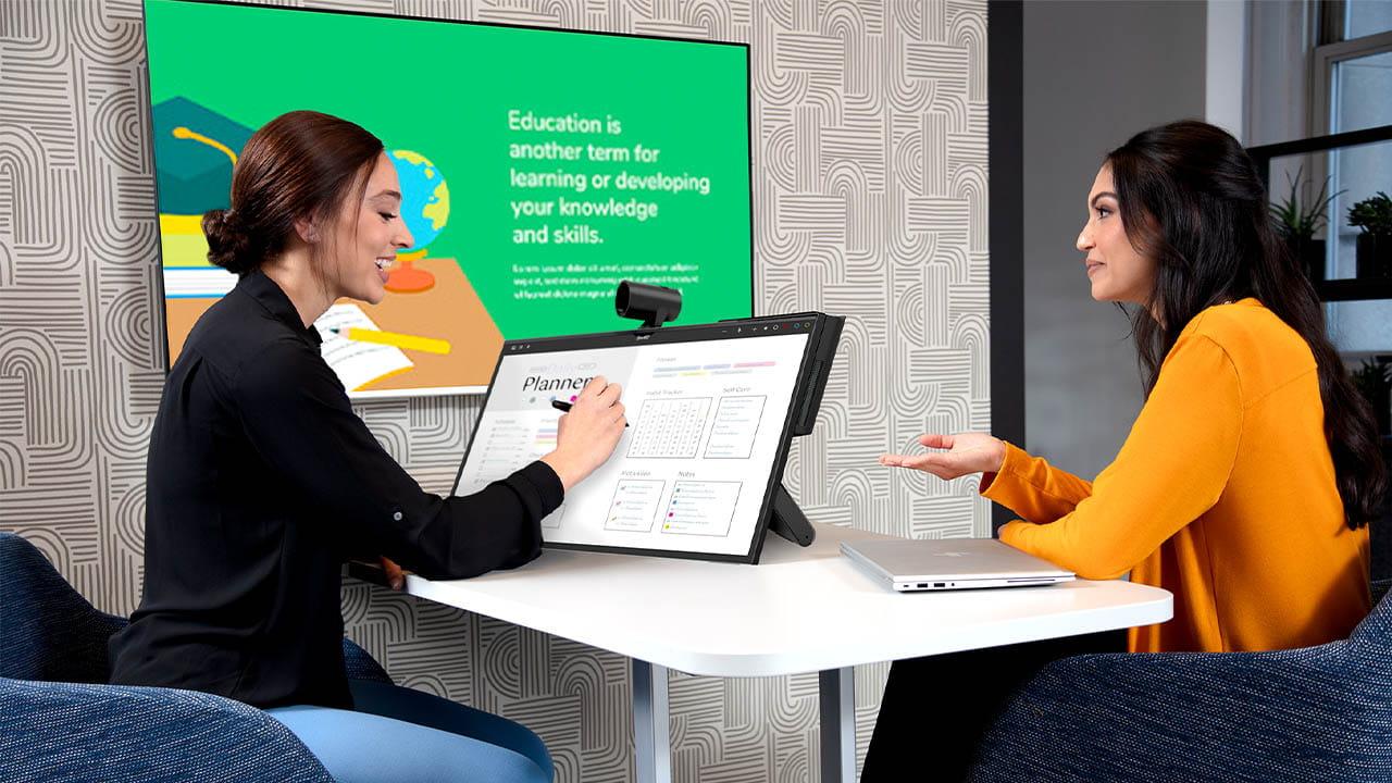 Two women collaborating with a SMART Board Mini Interactive Podium, showcasing a planner application.